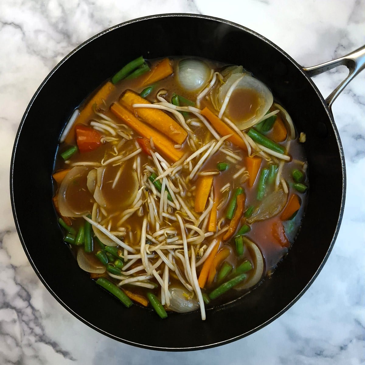 Sauce and bean sprouts added to the pan.
