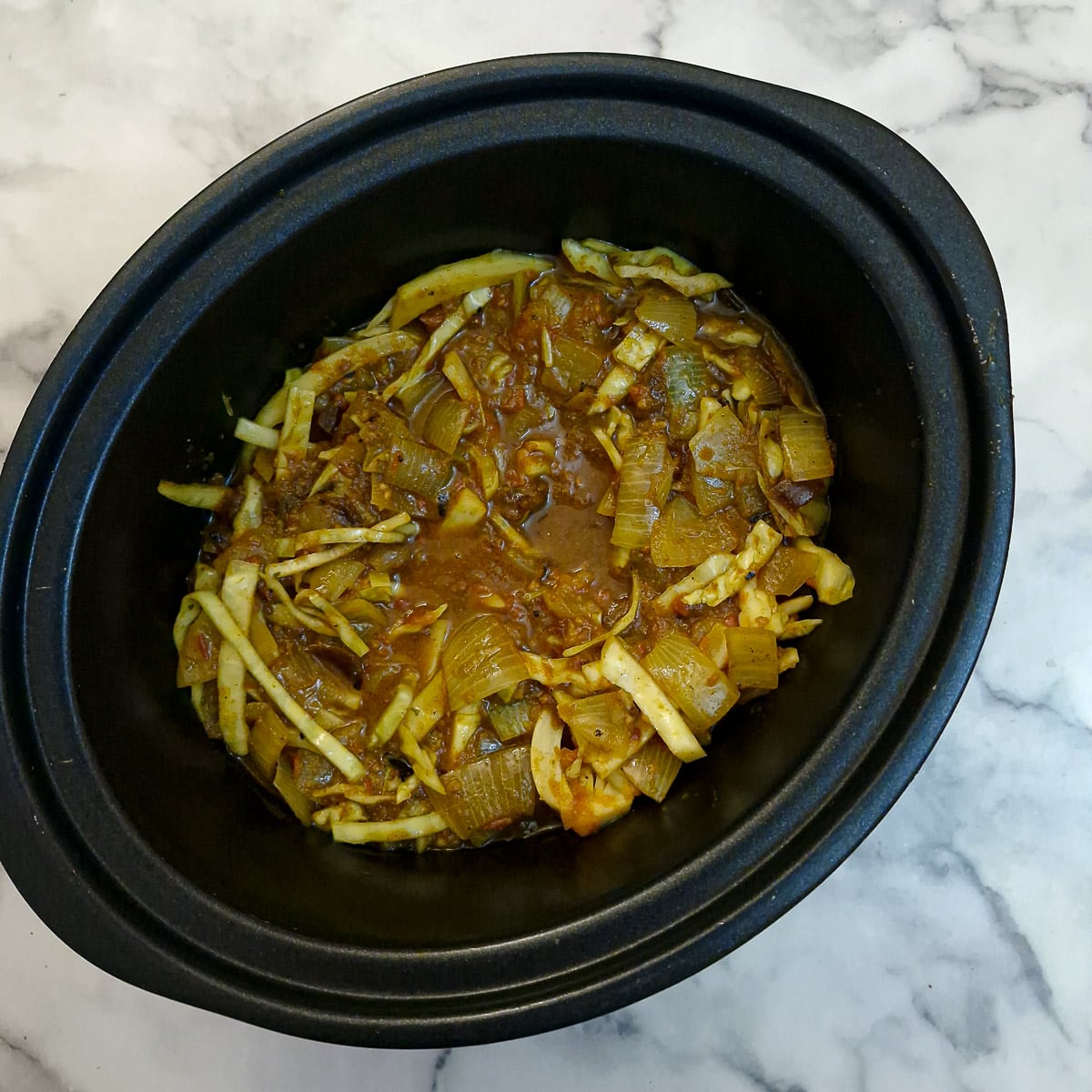 Step 6. The cabbage and onion mixture added to the meat in a slow cooker and covered with stock.