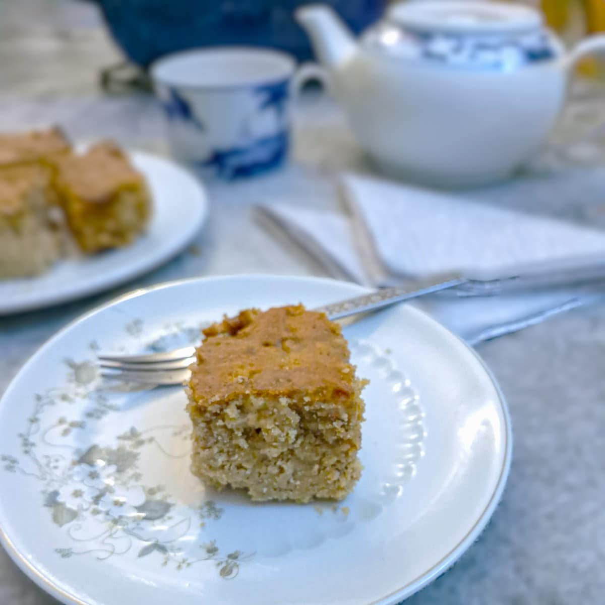 A slice of cold apple pudding cake on a small plate with a cake fork.