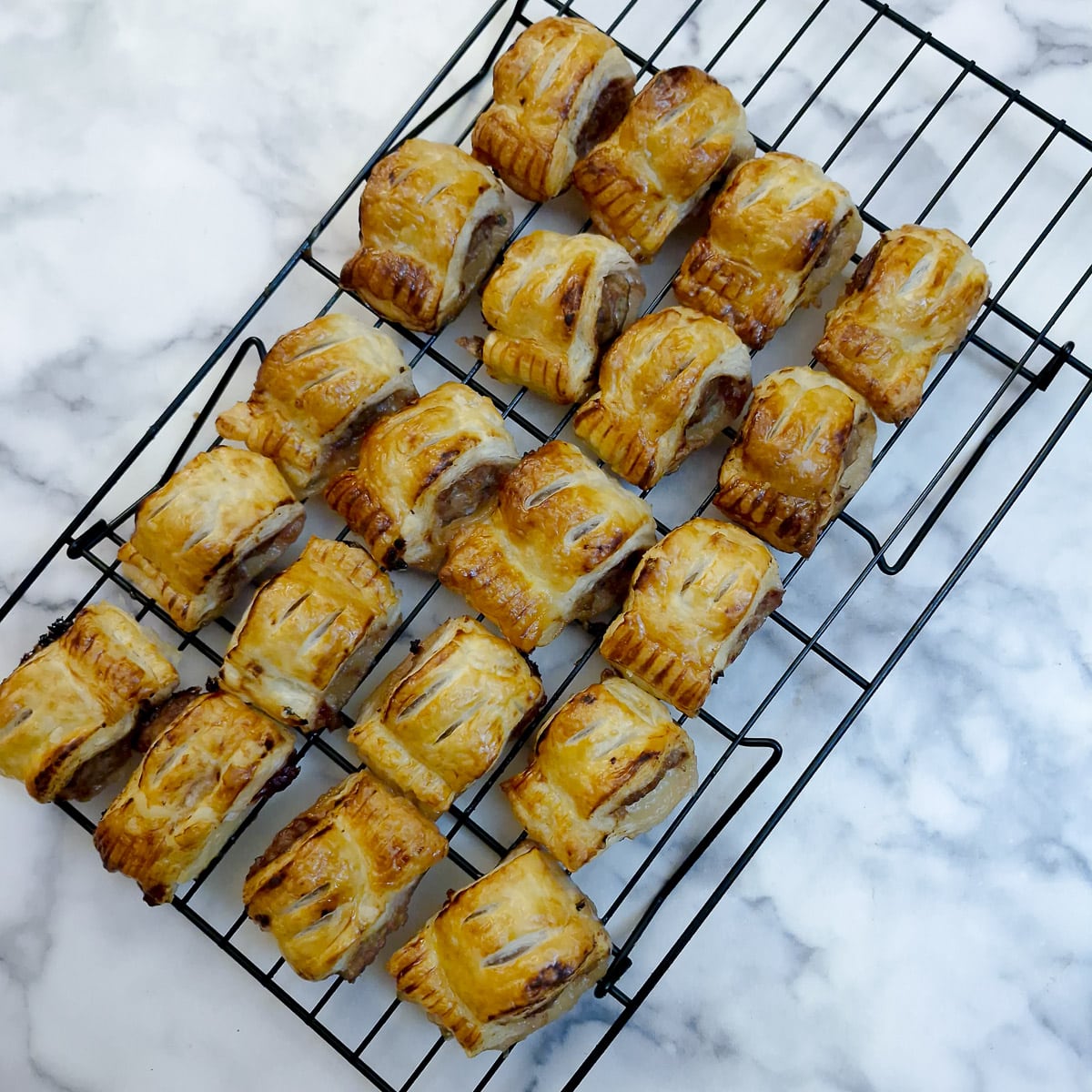 Sausage rolls cooling on a wire rack.