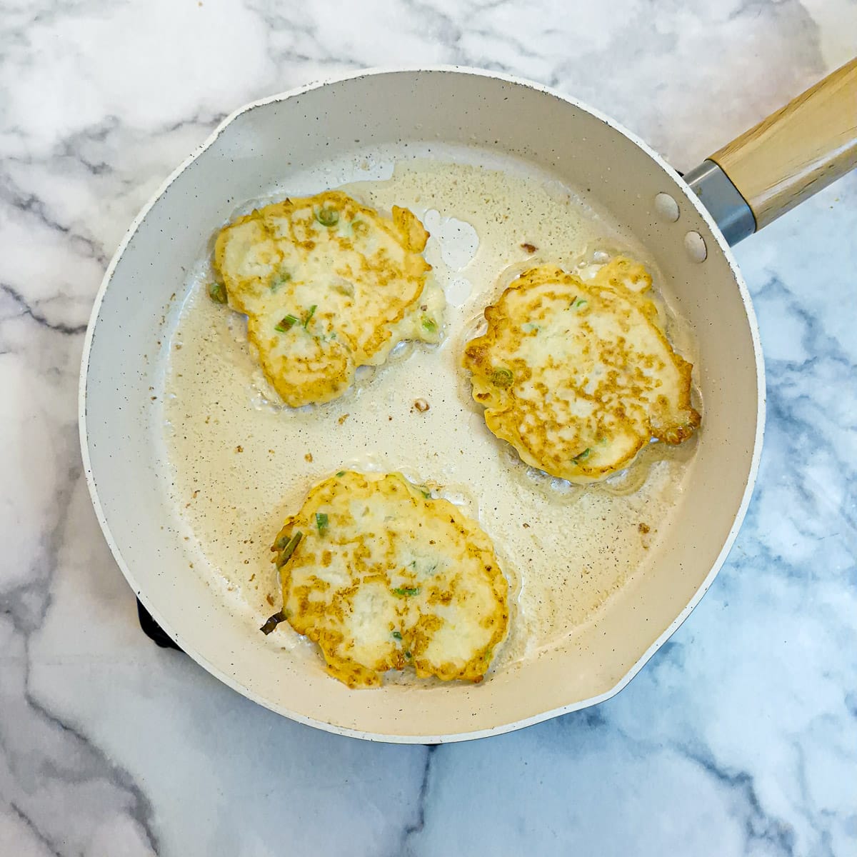 Step 5 - 3 browned potato cakes in a frying pan.