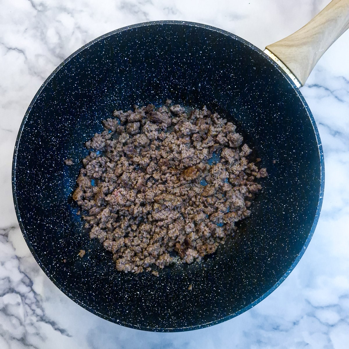 Ground beef browning in a wok.