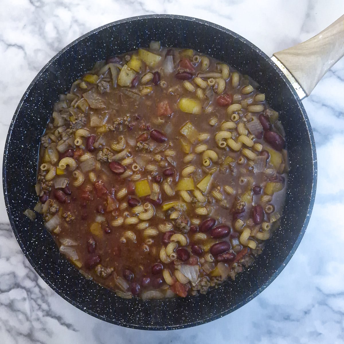 Stock, pasta, tomatoes and beans stirred into the meat and vegetables.