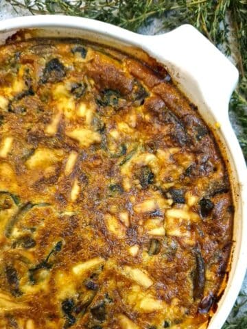 Overhead shot of a crustless mushroom, cheese and spinach quiche with springs of thyme on the side.