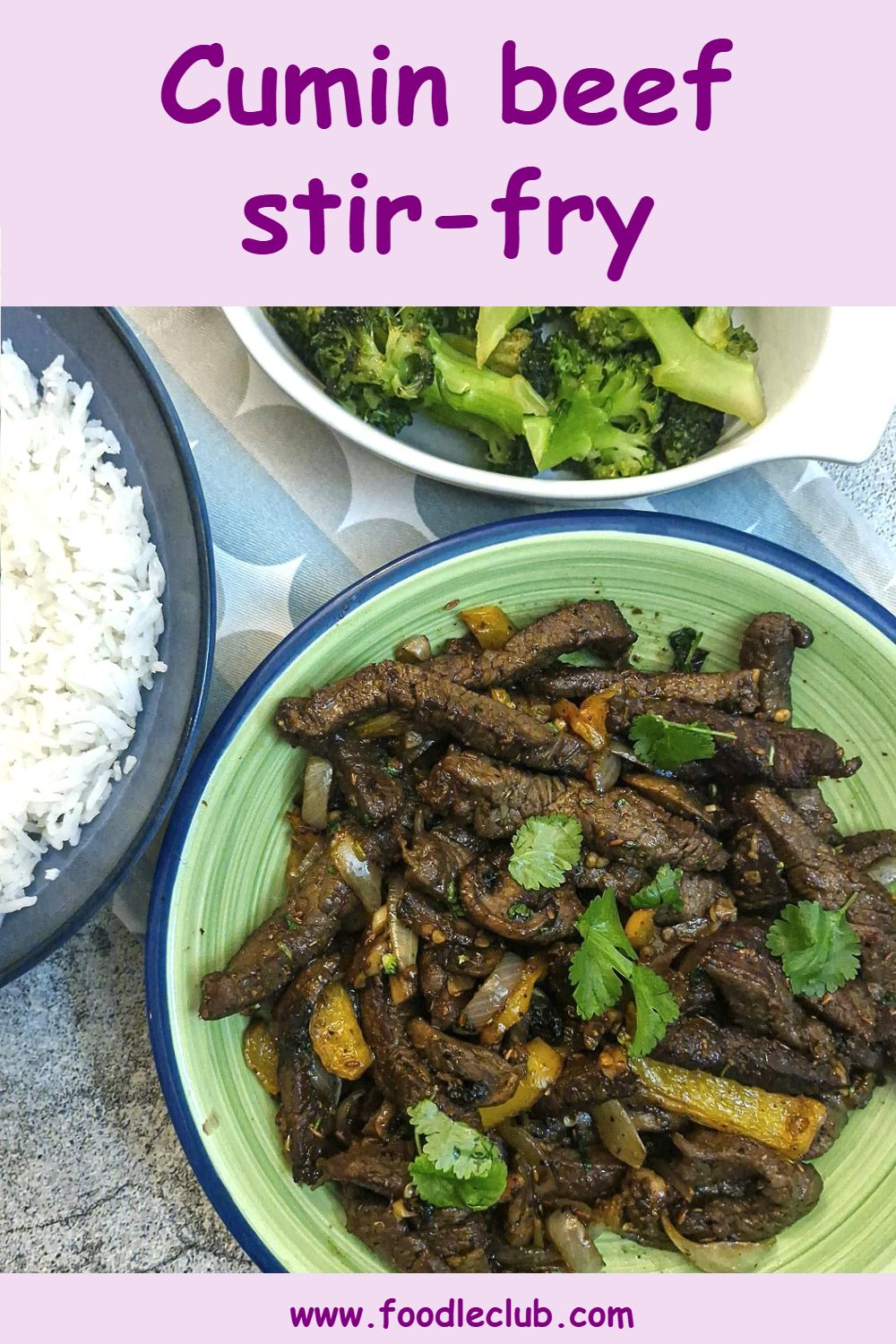 A dish of cumin beef stir-fry with dishes of rice and broccoli alongside.