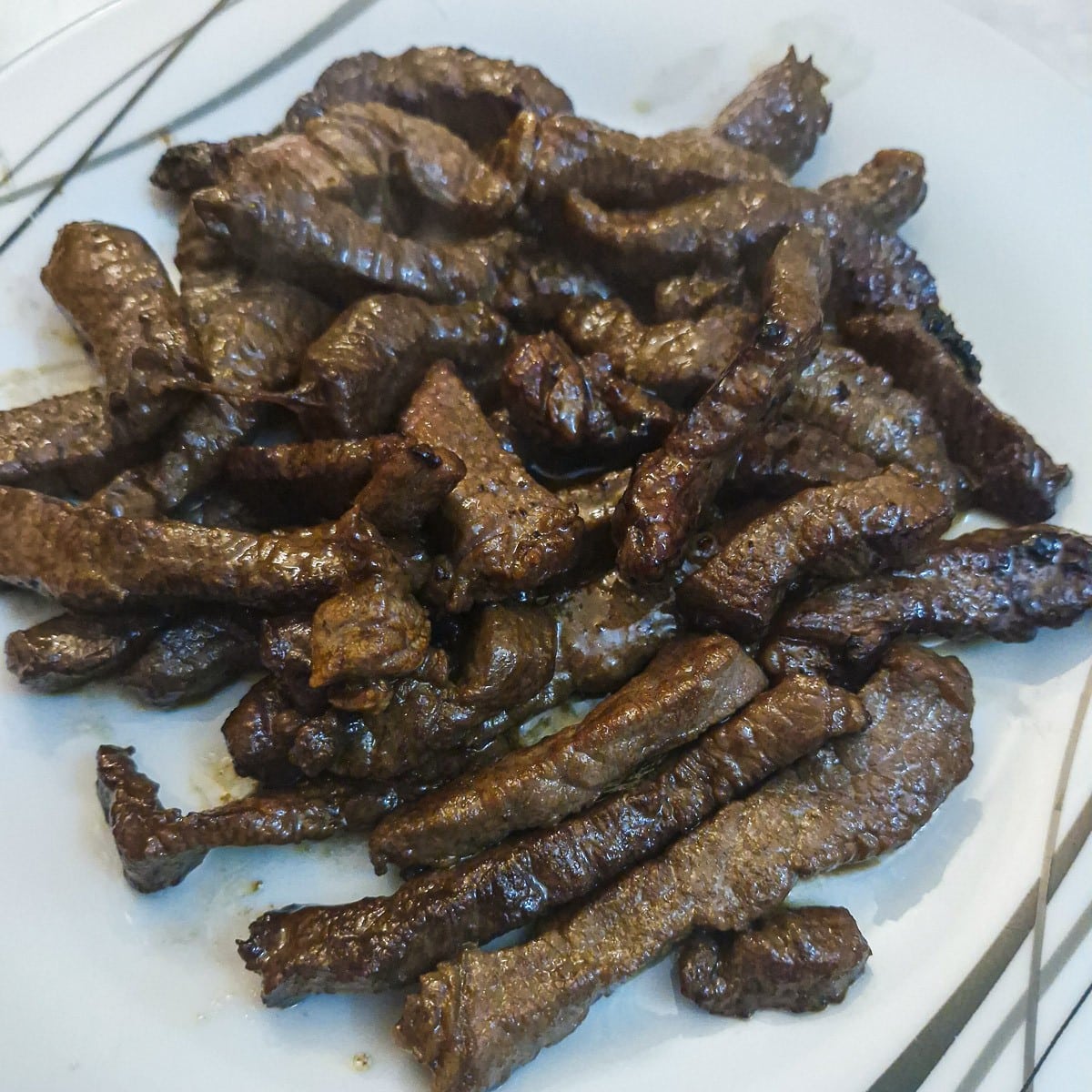 Browned steak strips transferred to a plate.