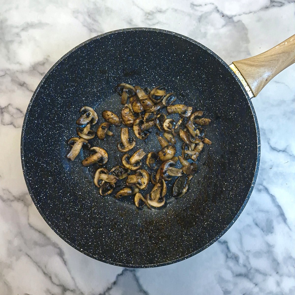 Sliced mushrooms browning in a wok.