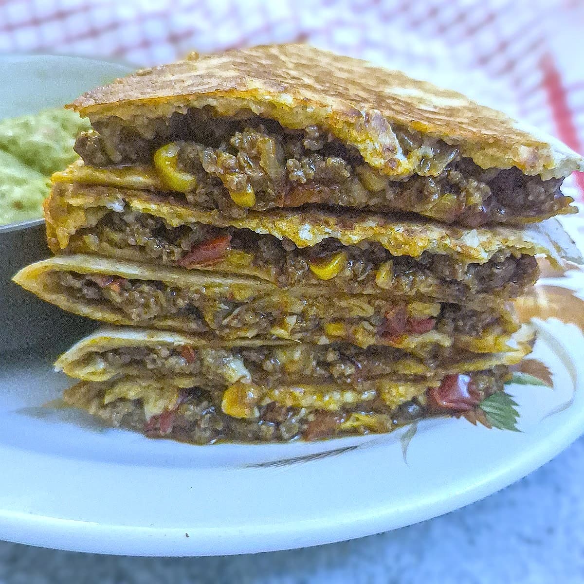 A pile of 5 slices of beef and corn quesadillas on a white plate.