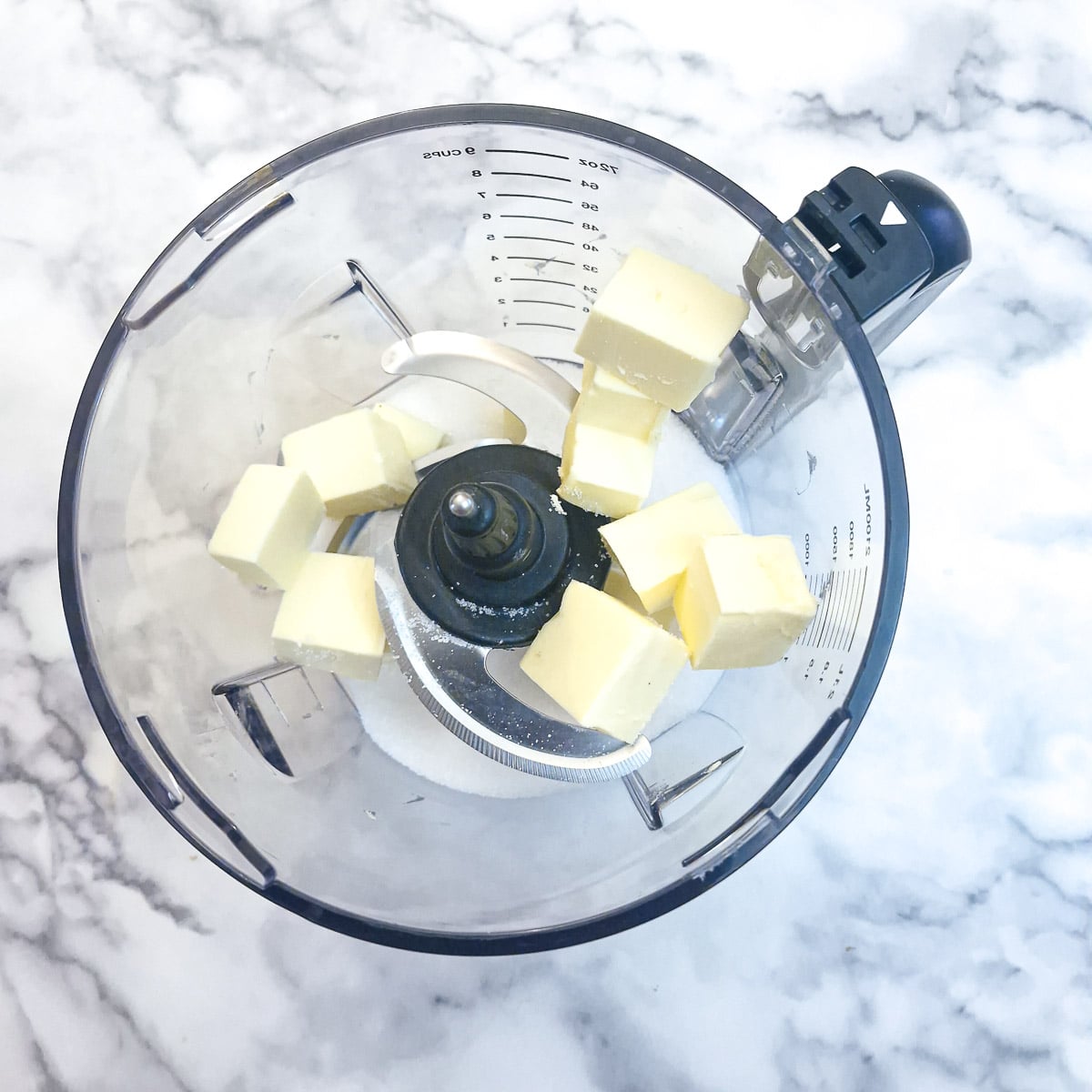 Butter and icing sugar in the bowl of a food processor.