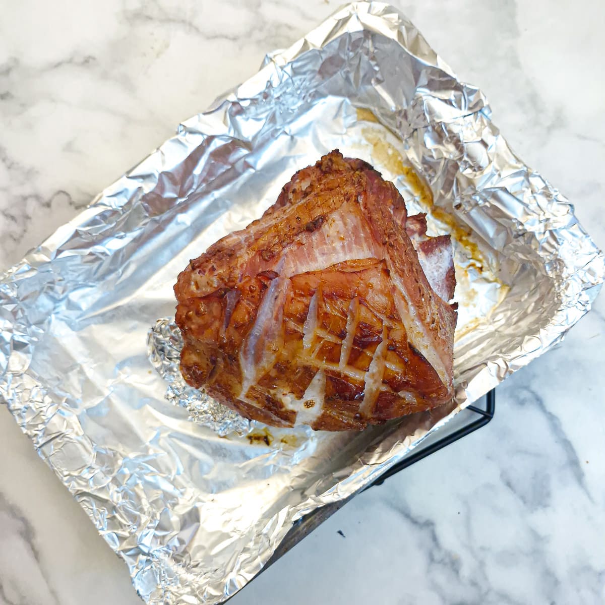 Partially roasted gammon in a baking tray before it is covered in honey glaze.