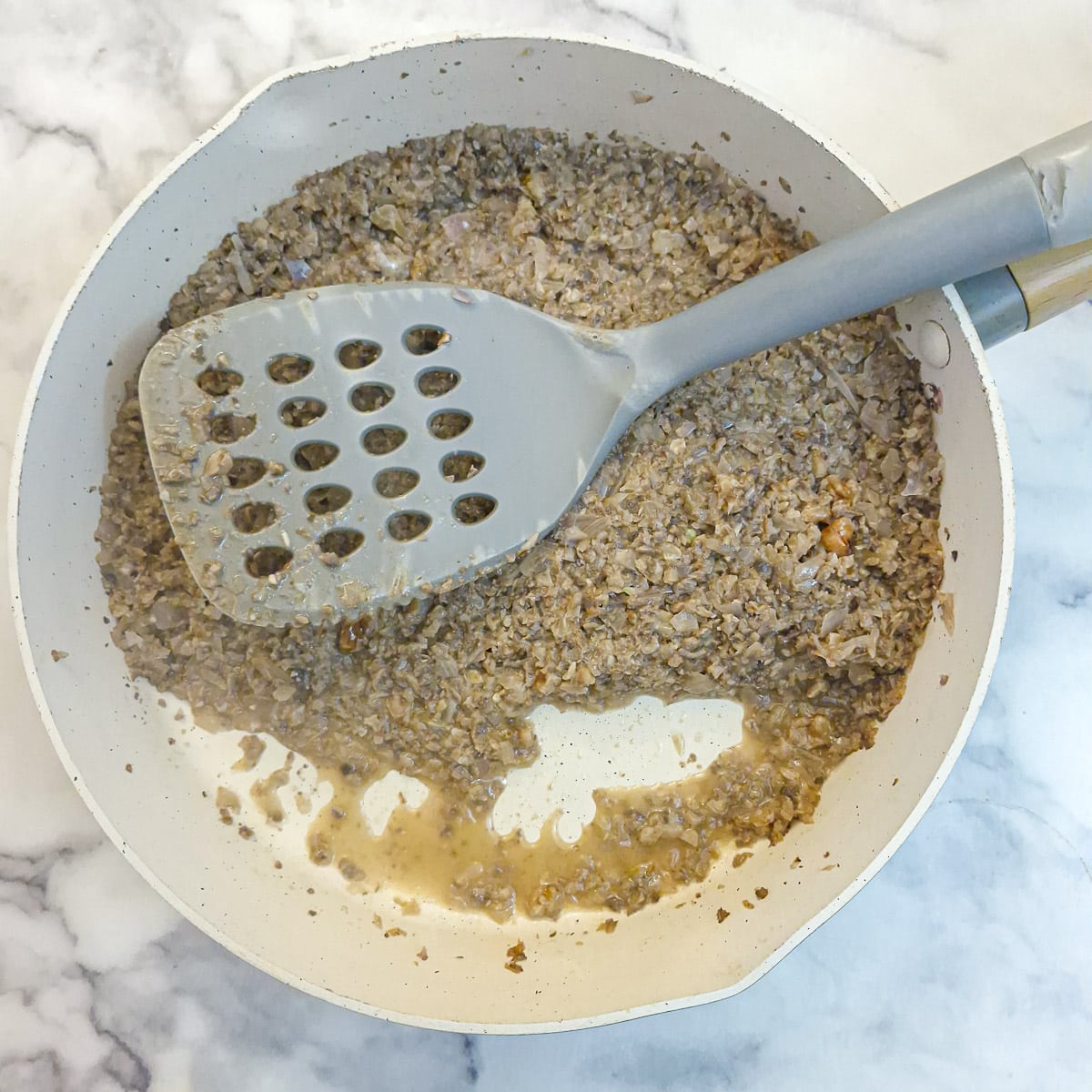 The mushroom mixture after having cooked in a covered pan for 5 minutes. The moisture is visible around the edges of the pan.
