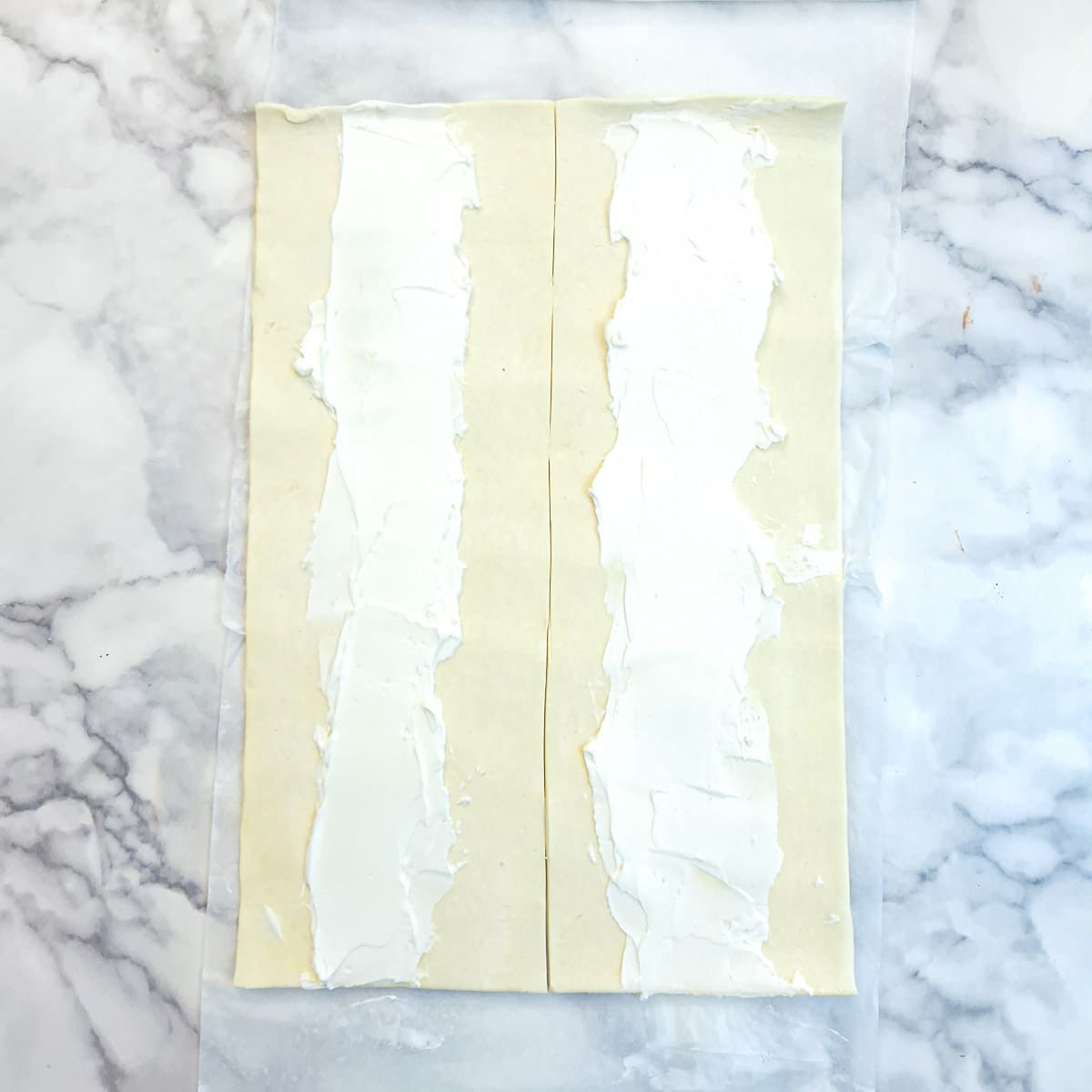 Two strips of puff pastry spread with cream cheese.