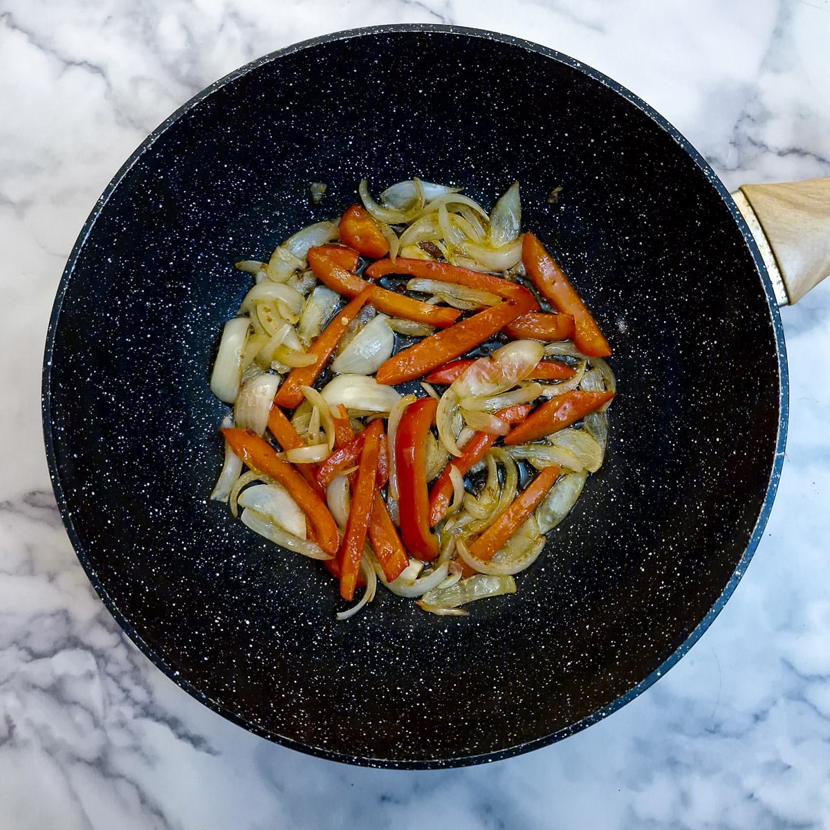 Sliced onion and capsicum (or bell peppers) in a wok.