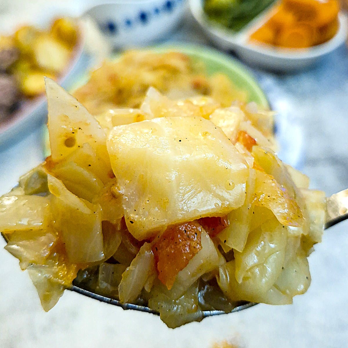 Close up of a spoonful of braised cabbage with tomatoes and onions.