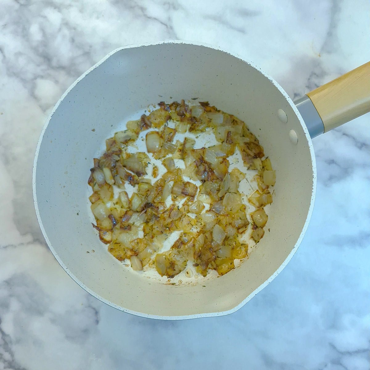 Chopped onions softening in butter in a saucepan.