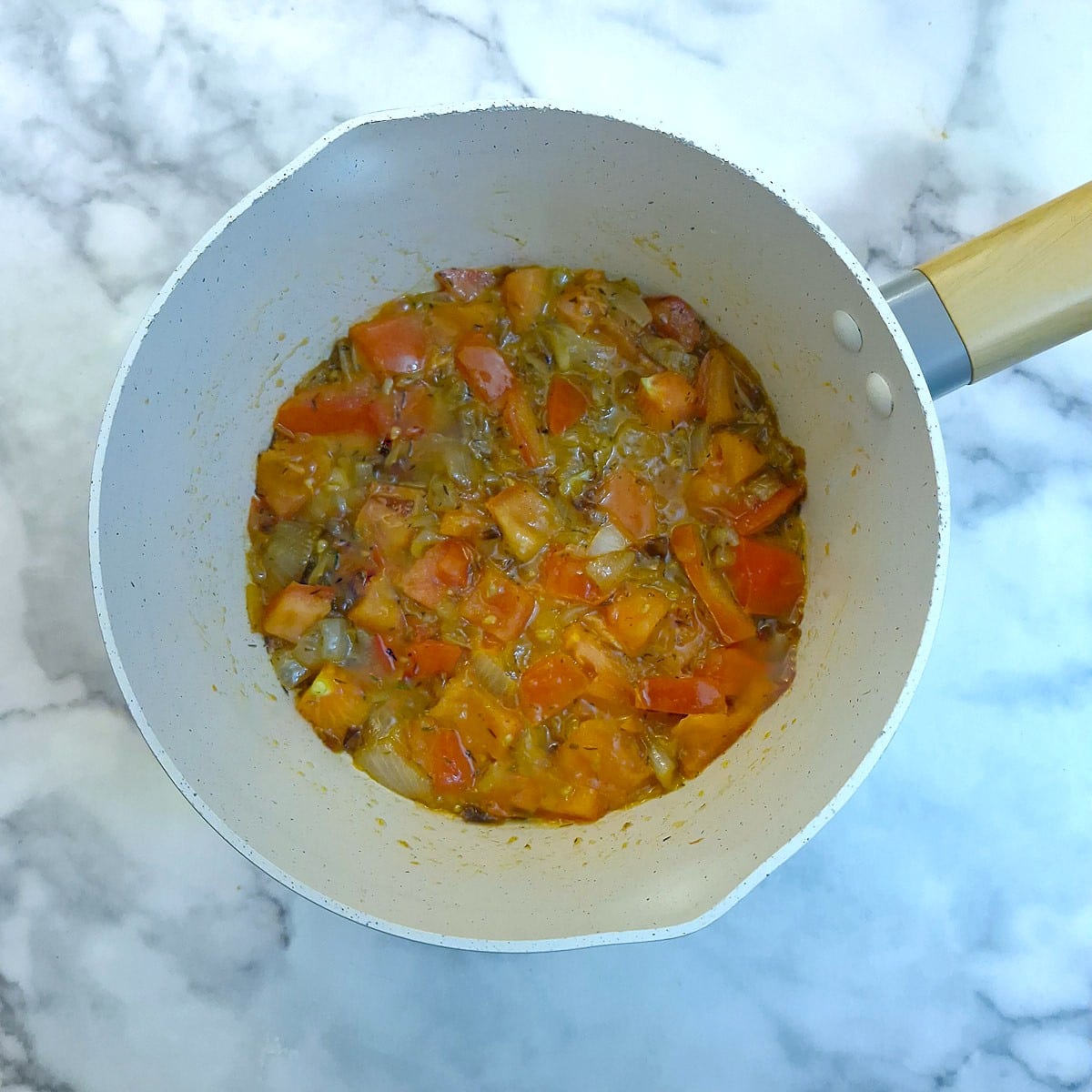 Tomatoes and dried thyme added to the onions in a saucepan.