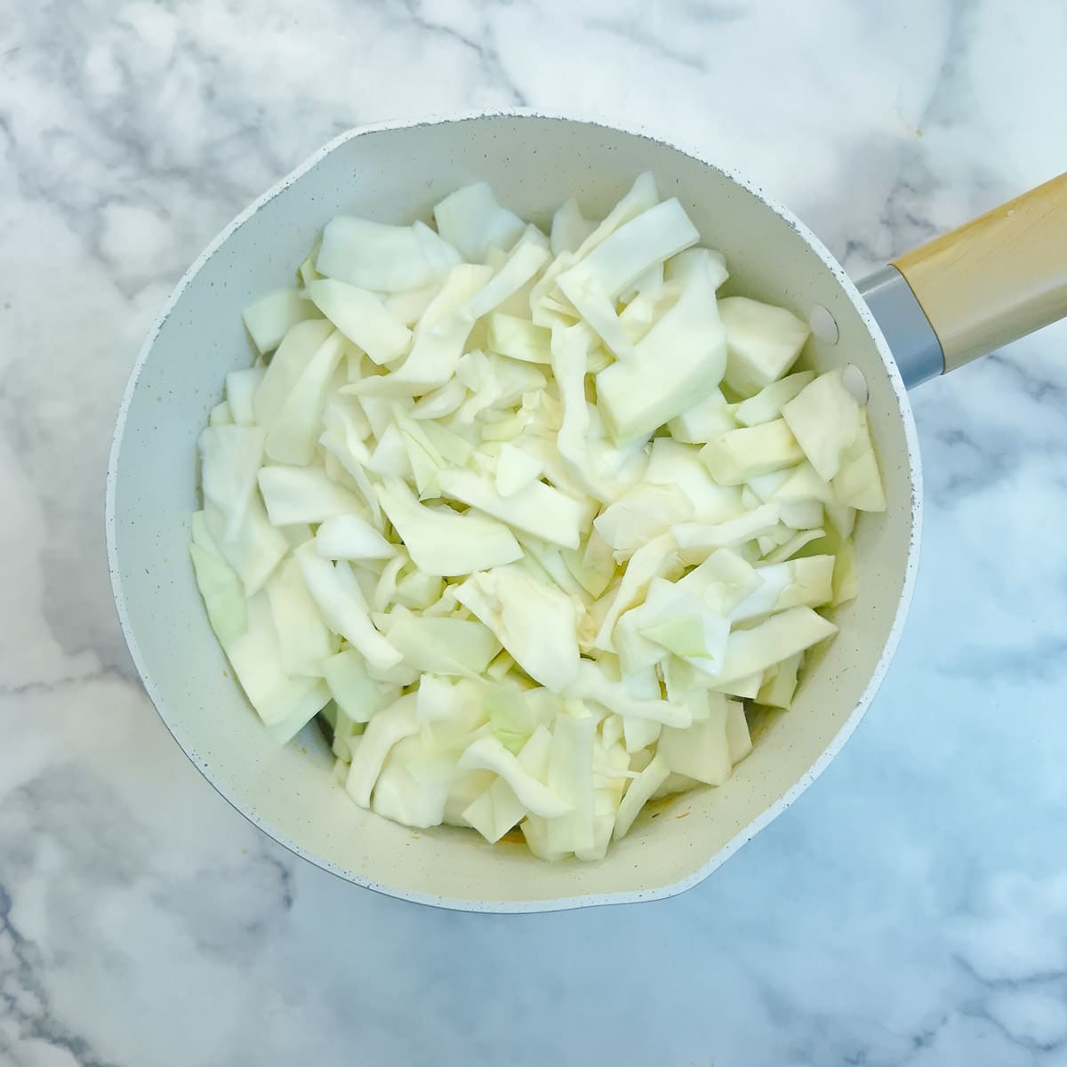 Raw chopped cabbage added to the saucepan. The saucepan looks rather full!