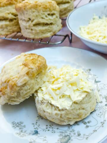 Two halves of a cheese scone - the bottom half topped with grated cheese and the top half propped up alongside.
