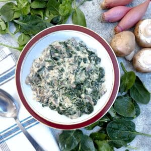 A dish of spinach and mushrooms with cream cheese sauce.