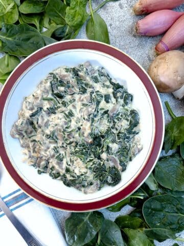 A dish of spinach and mushrooms with cream cheese sauce.