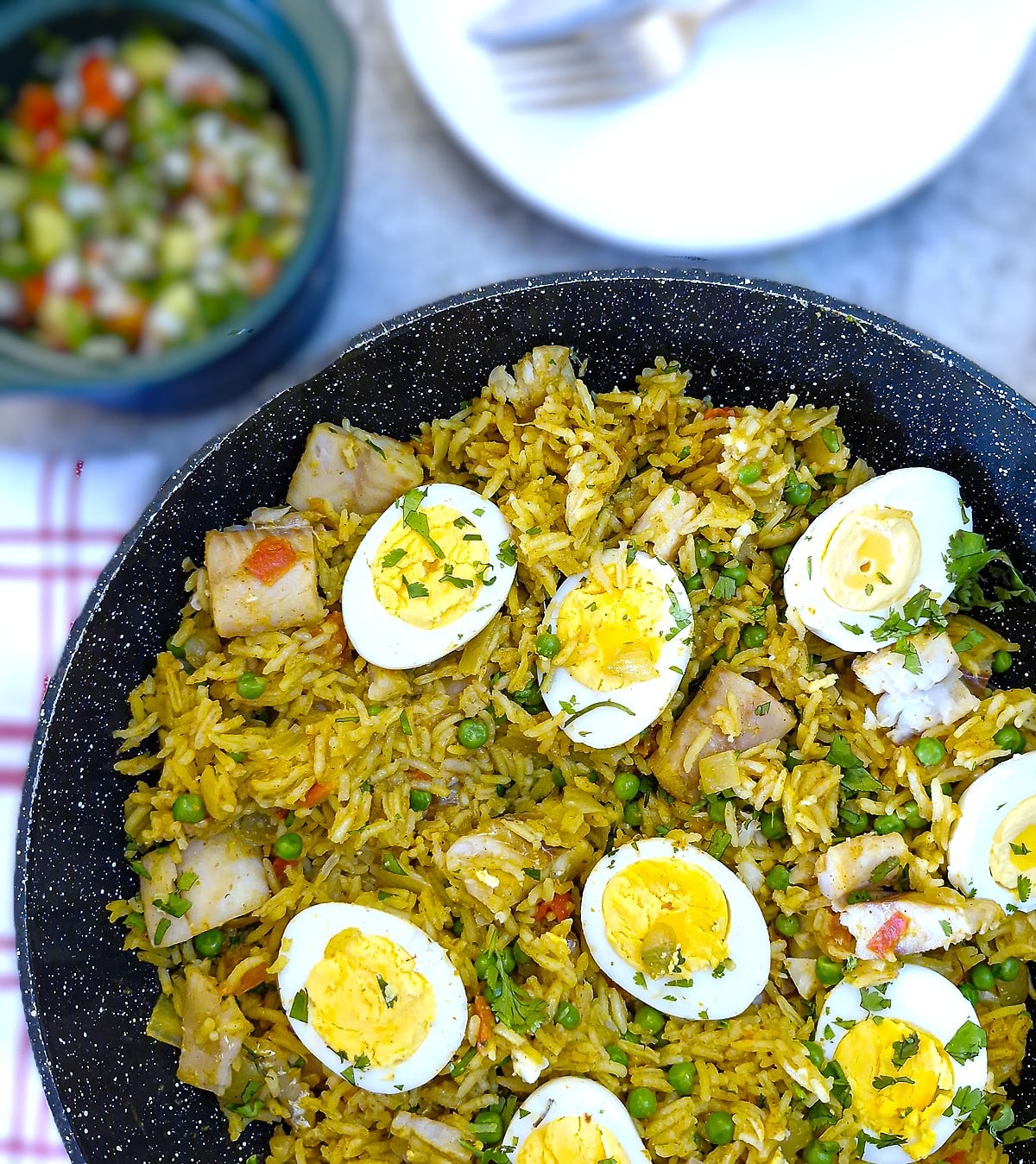 Overhead shot of curried fish and rice pilaf with hard-boiled eggs arranged on top.