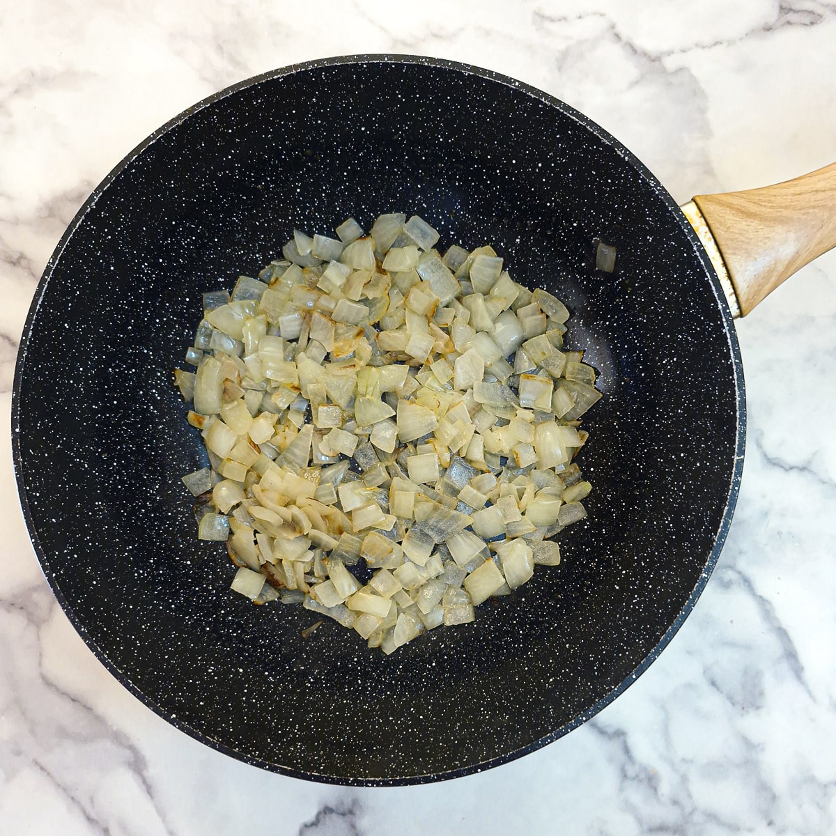 Chopped onions softening in a frying pan.