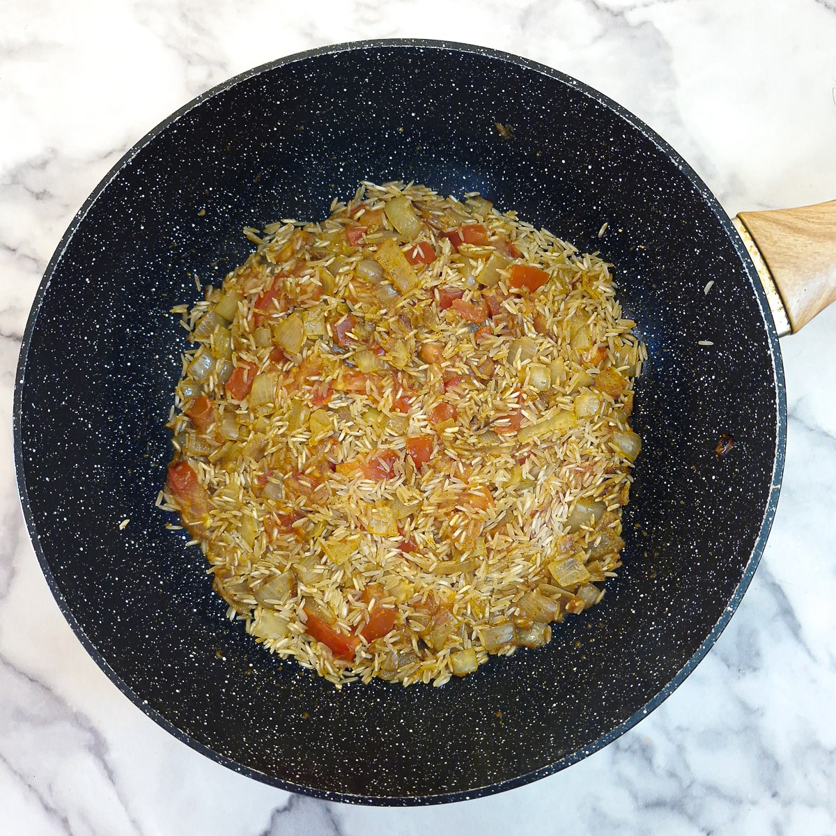 Uncooked rice stirred into the tomato and onion mixture.