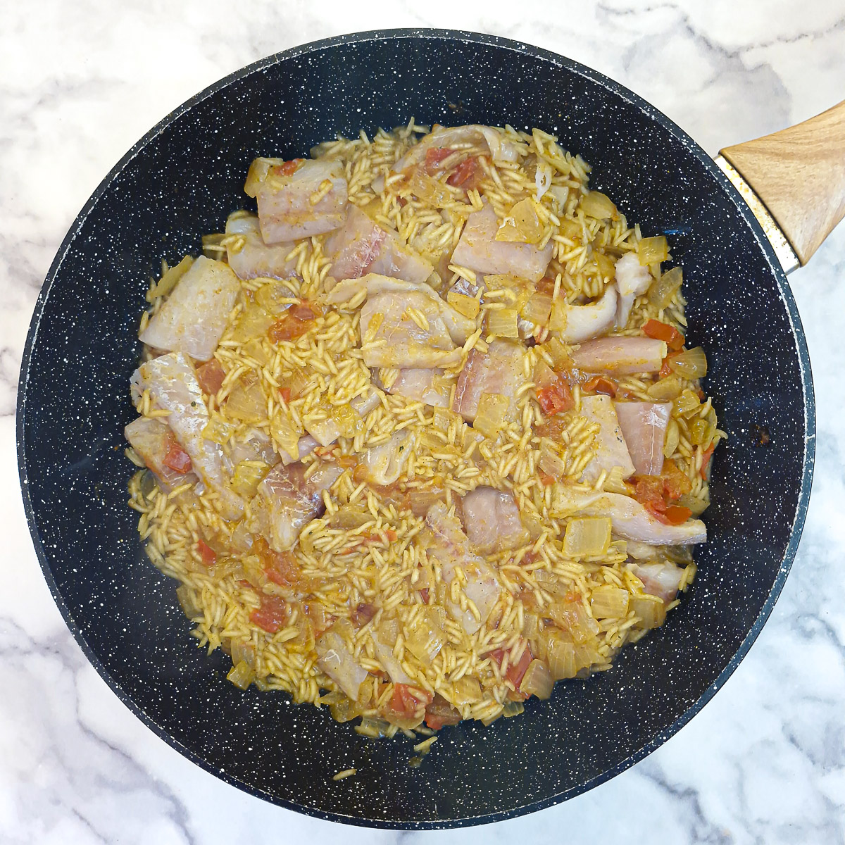 Pieces of fish nestled into the rice mixture.