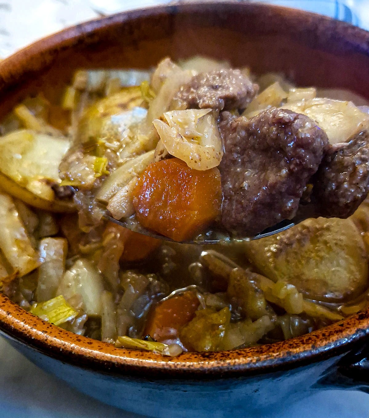 Close up of a spoonful of lamb and vegetables being lifted from the casserole dish.