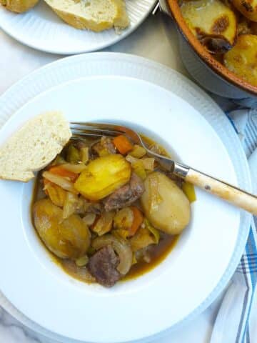 Close up of a helping of lamb potjie on a white plate.
