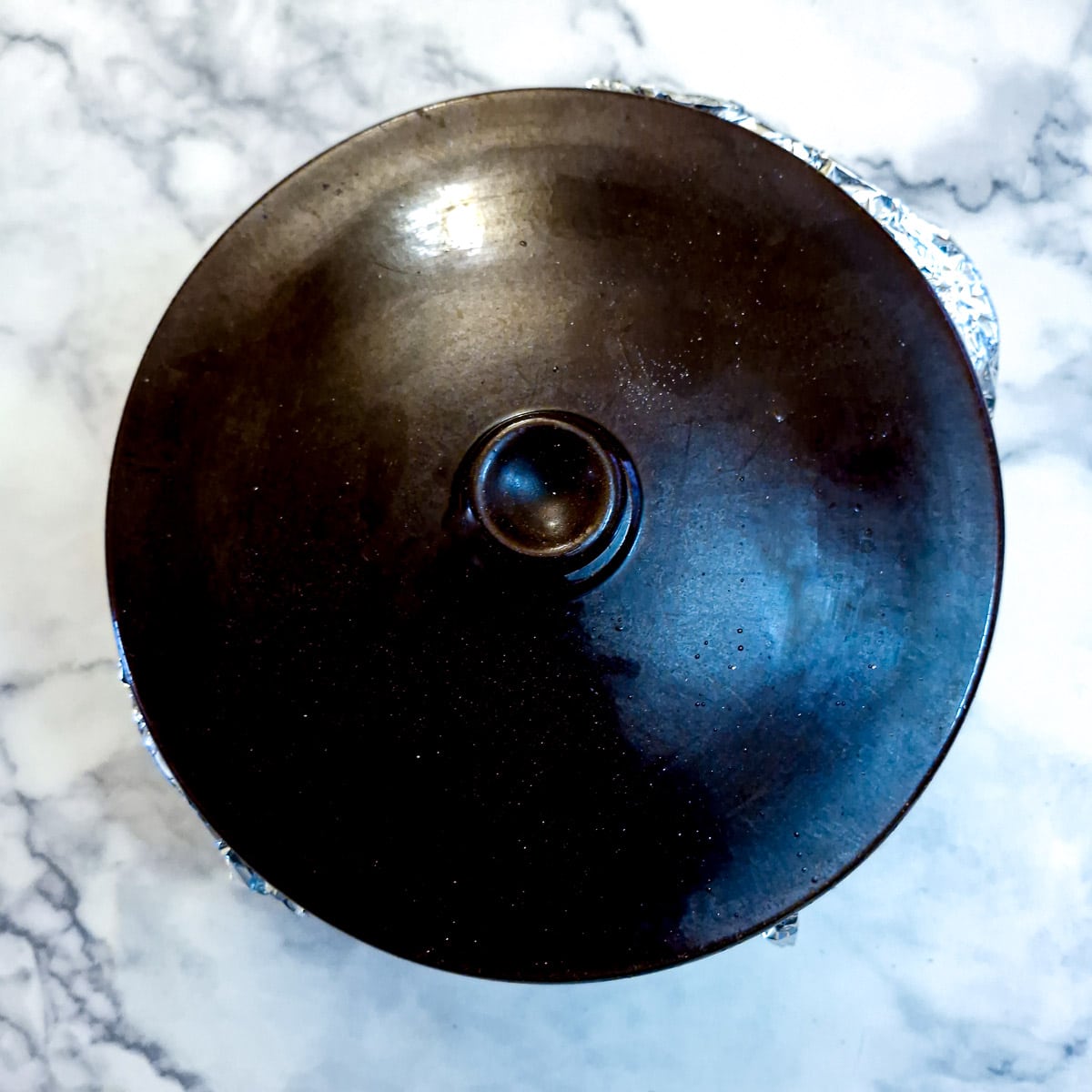 A layer of tin foil has been added over the baking parchment and the lid of the casserole placed on top.