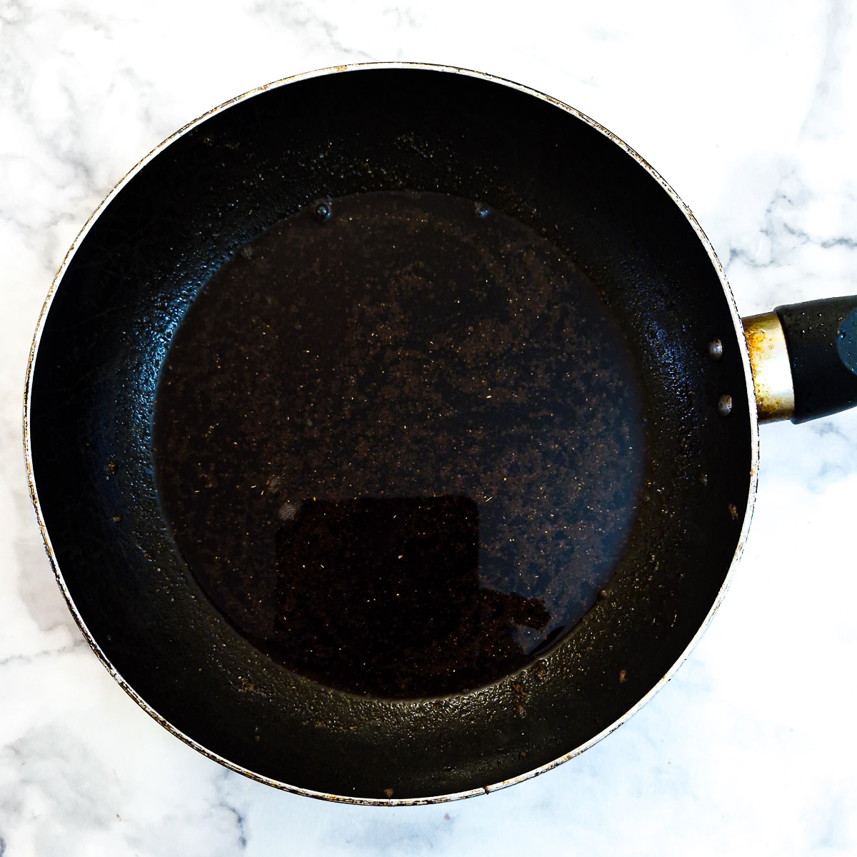 Spices and red wine in a frying pan.
