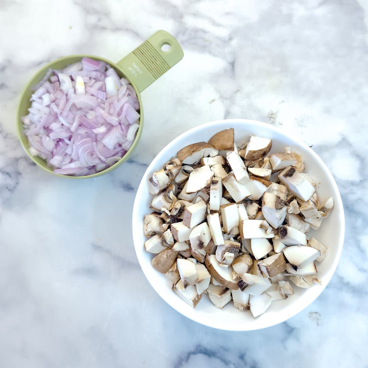 Step 1 - A dish of chopped mushrooms and a measuring cup filled with chopped shallots.
