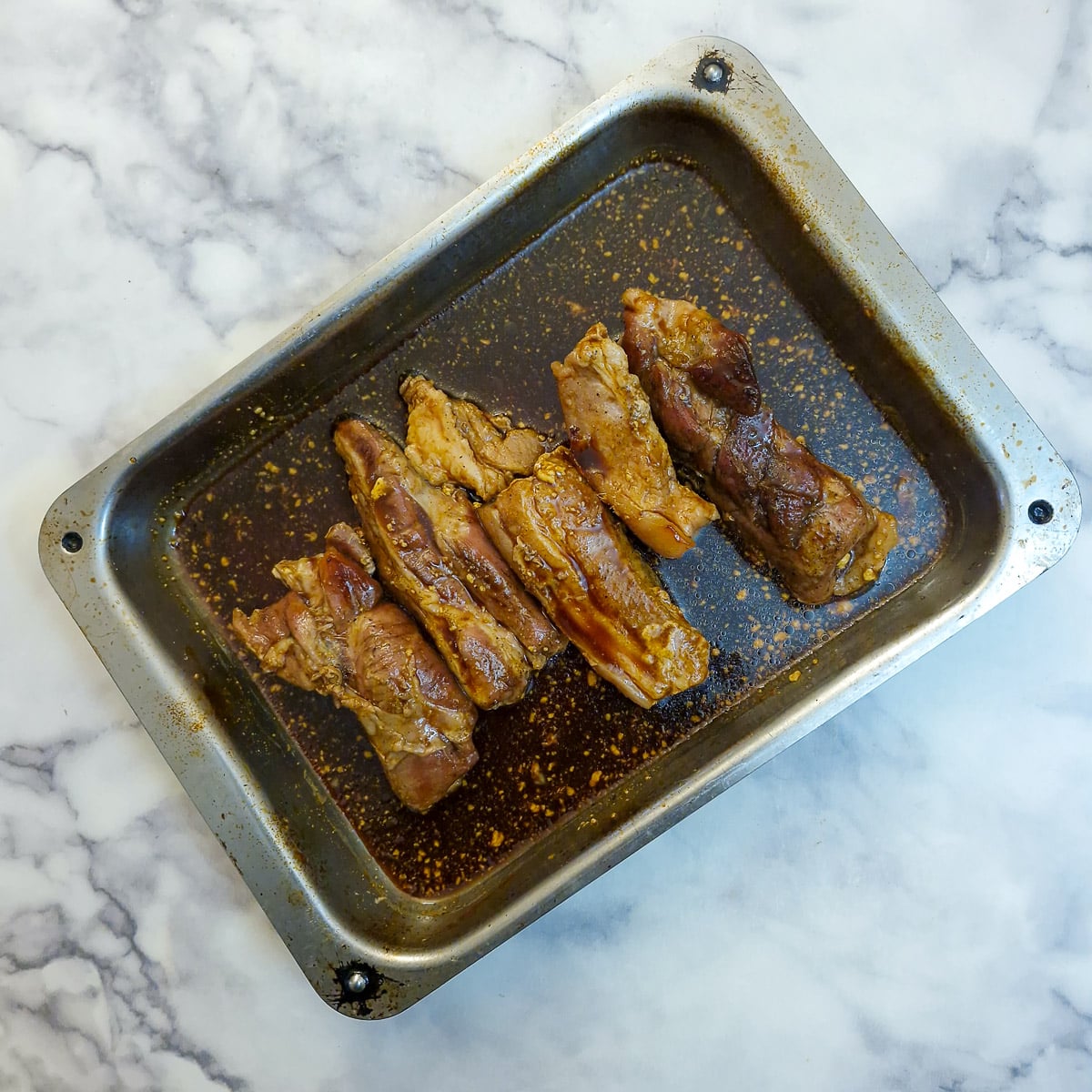 5 pork belly slices covered in glaze in a roasting pan.