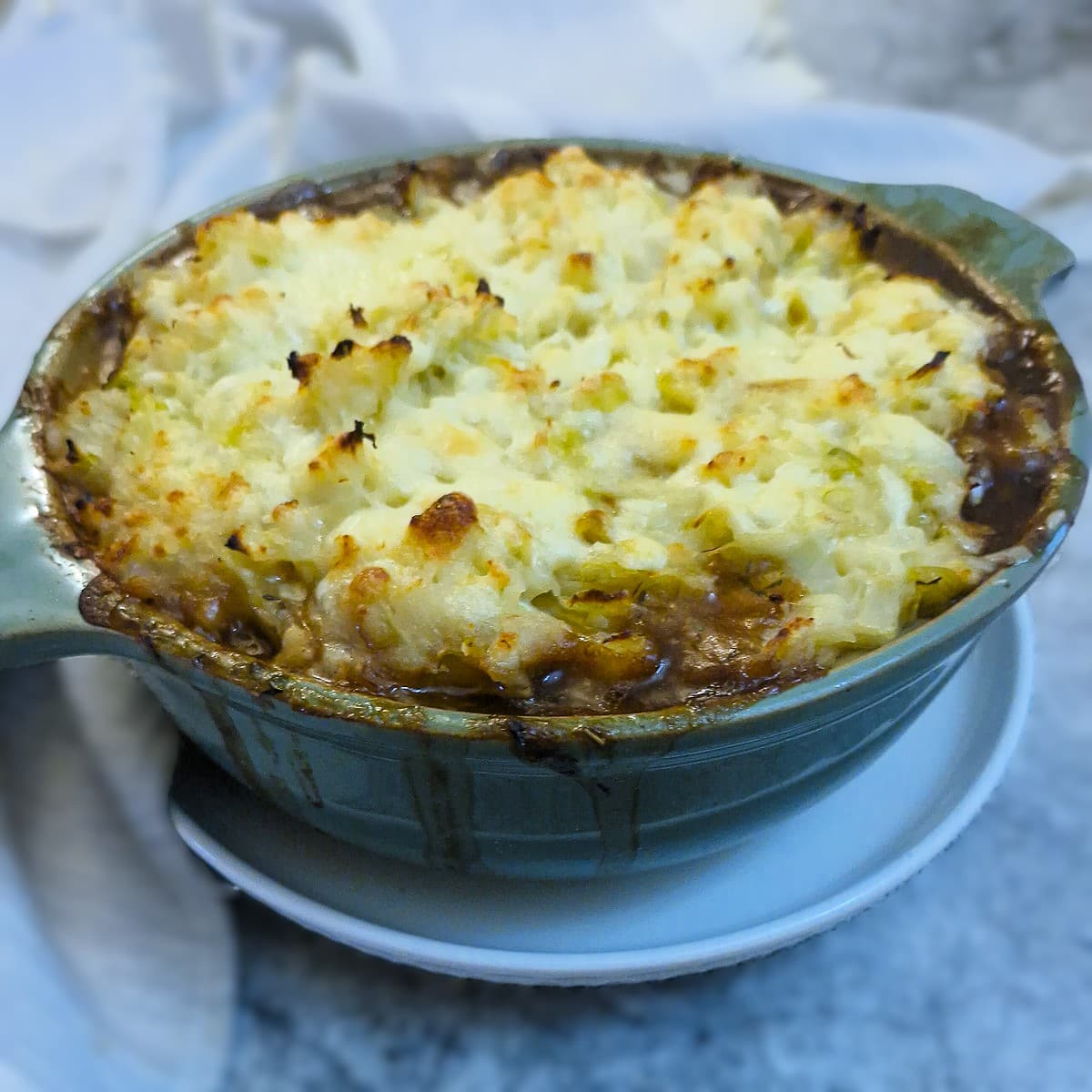 Colcannon-topped sausage and onion bake in a green casserole dish.