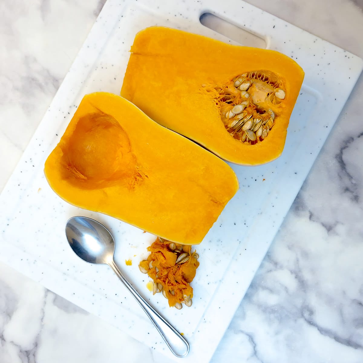 Two halves of a butternut; one of them has had the seeds scooped out.