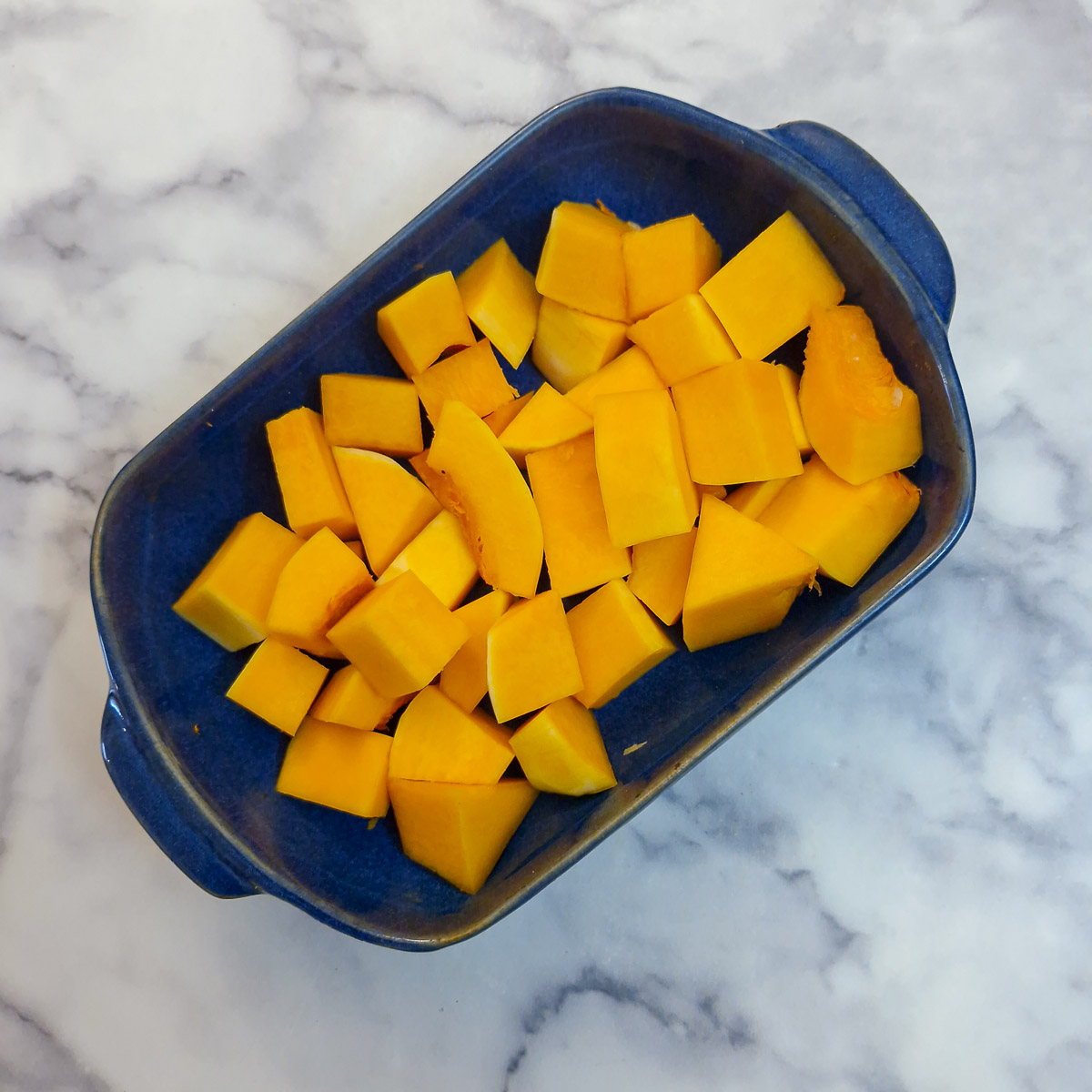 Chunks of butternut in a blue baking dish.