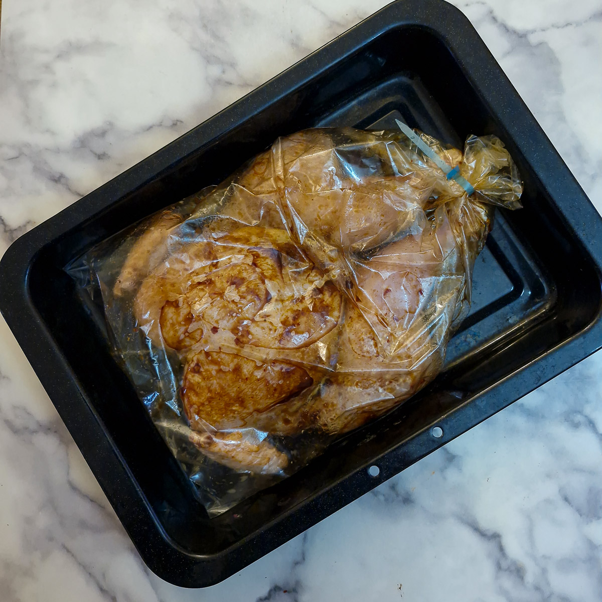 Step 3. A whole marinated chicken sealed in an oven bag and placed in a roasting tin.