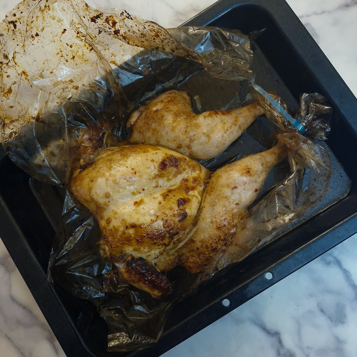 Step 4. A cooked roasted chicken in an oven bag that has been cut open.
