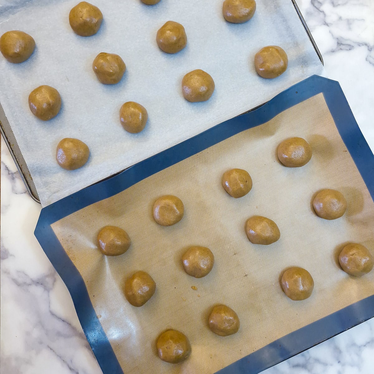 Step 5 - 24 balls of ginger snap dough arranged on 2 lined baking sheets.