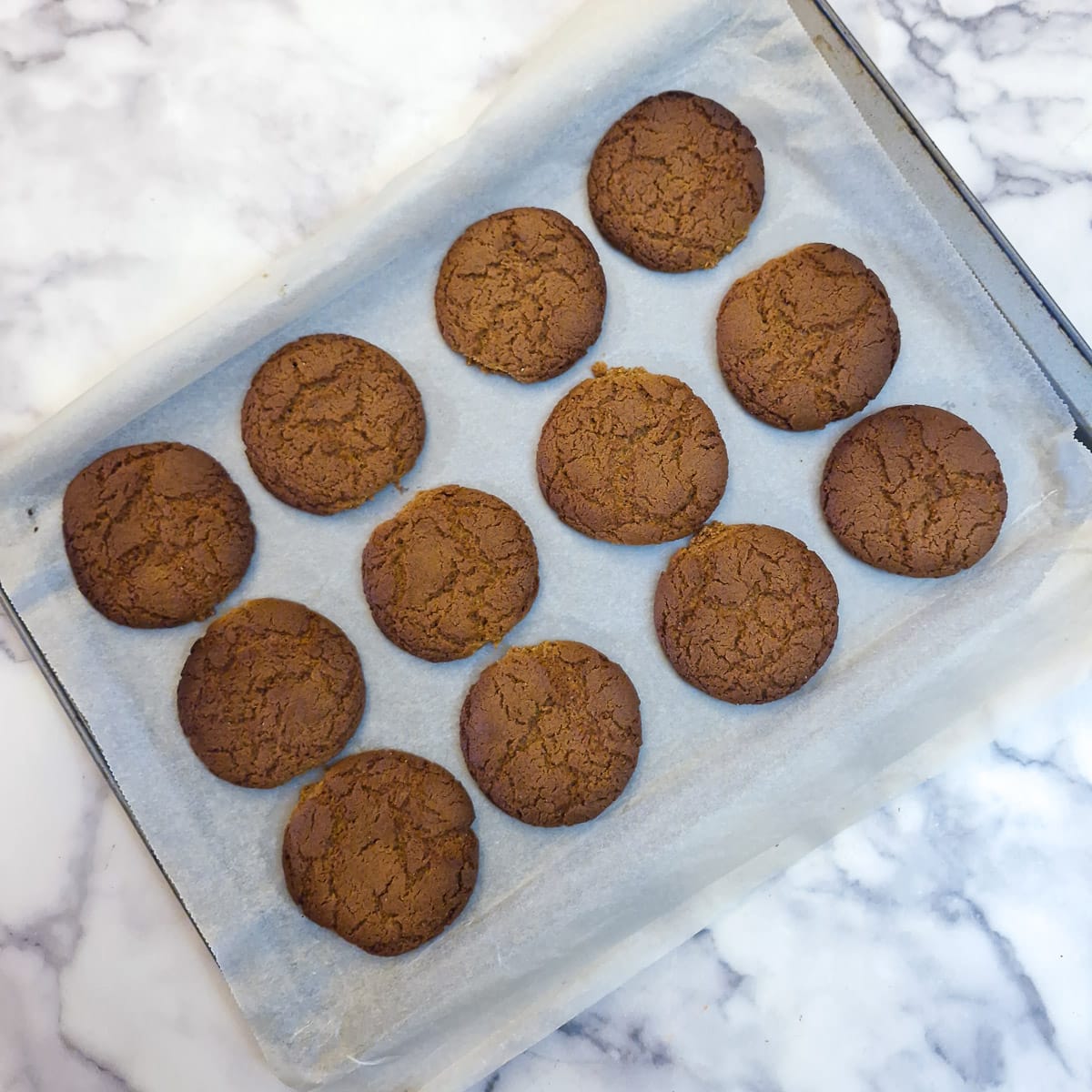 Step 6 - 12 baked ginger snap cookies on a baking sheet.