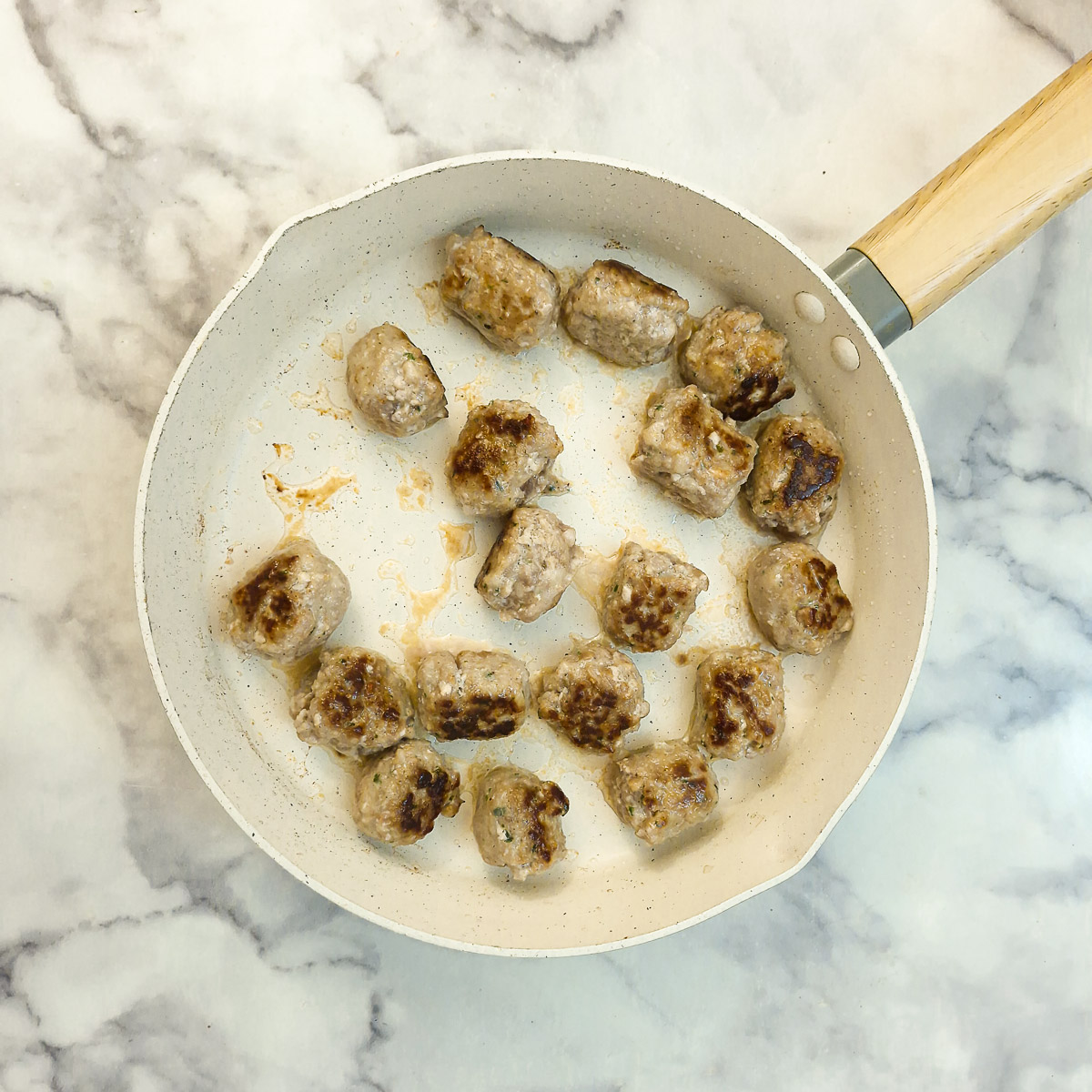 Step 6 - sausage balls being browned in a frying pan.