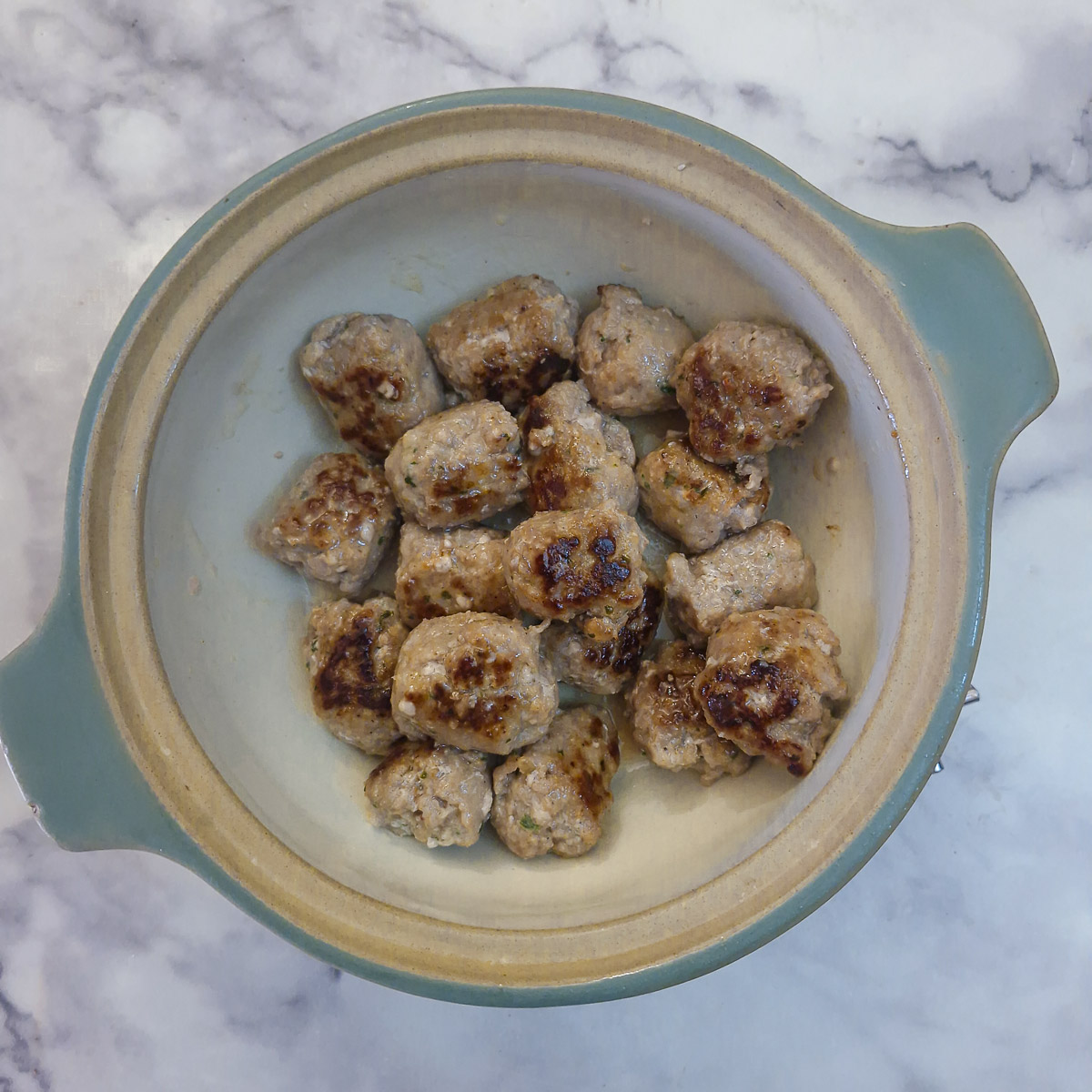 Step 7 - browned sausage balls transferred into a casserole dish.
