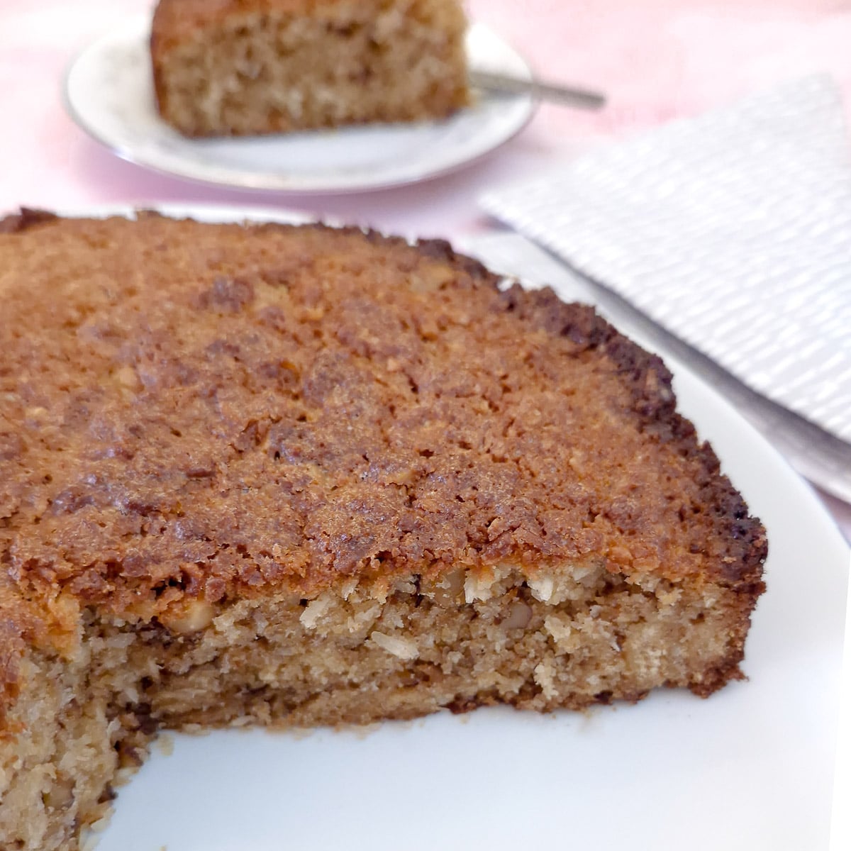 A cross-section of a lemon and coconut walnut cake with a slice cut out,showing the texture.