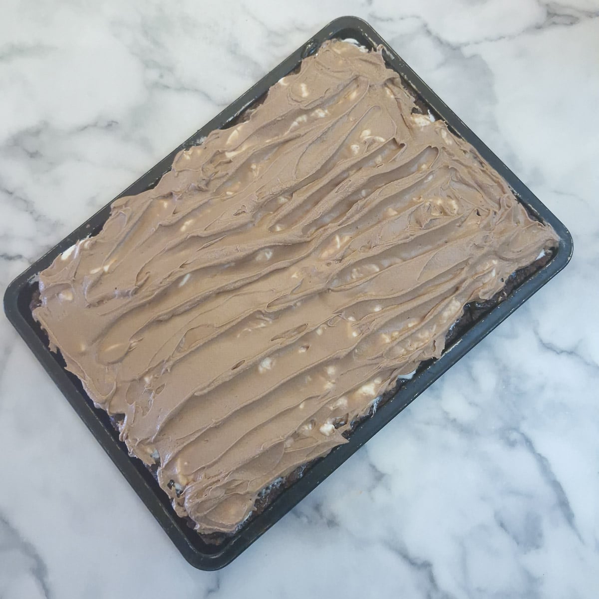 Whipped chocolate ganache layered over the wagon wheel traybake.
