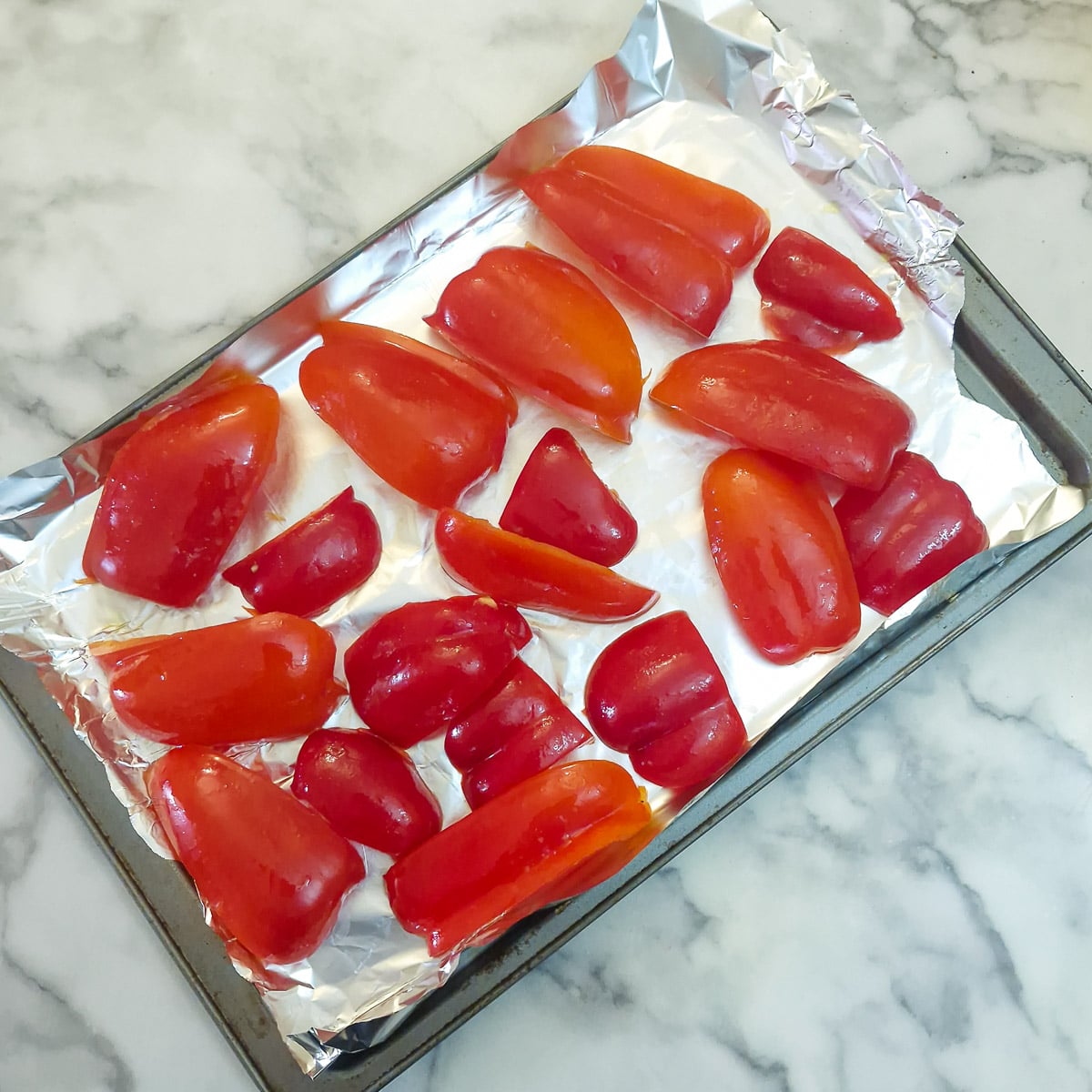 Step 1 - slices of raw red pepper on a baking sheet.