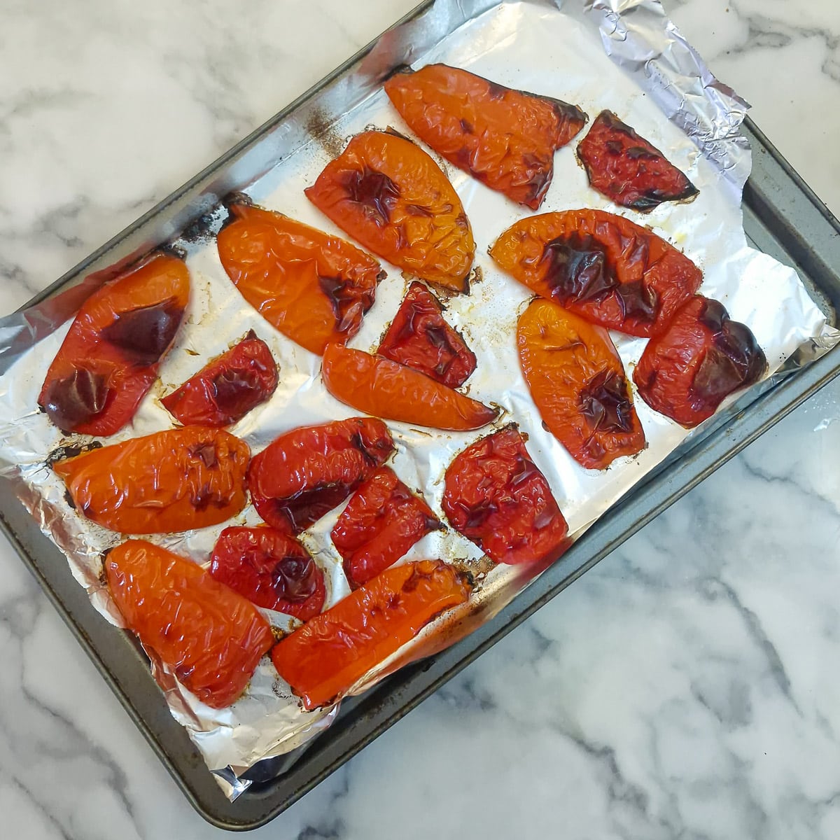 Step 2 - slices of slightly charred roasted red pepper on a baking tray.