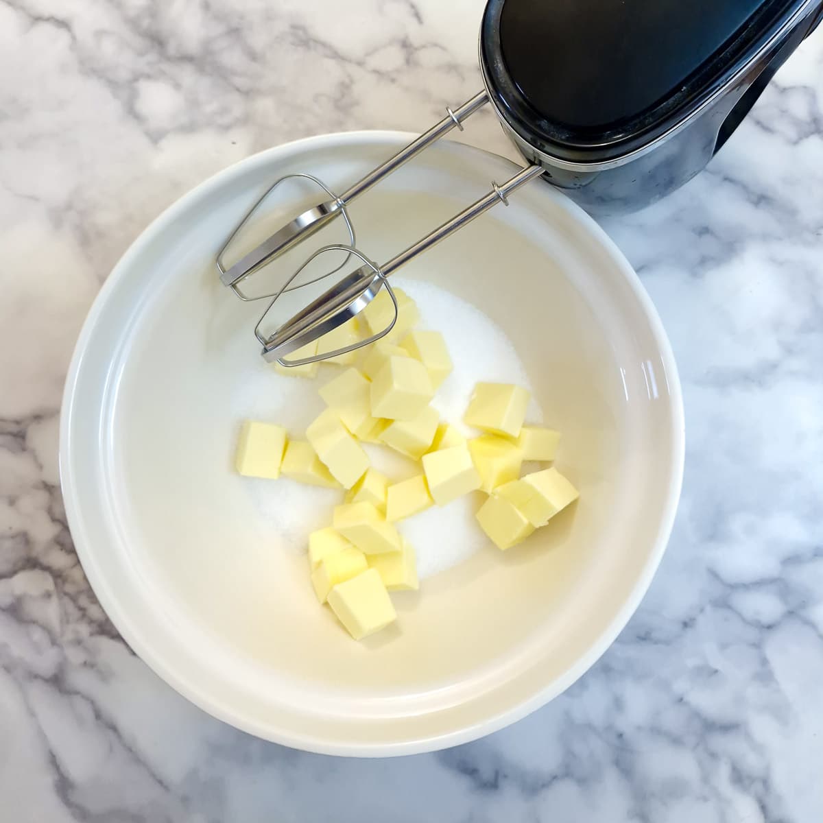 Sugar and cubed butter in a mixing bowl.