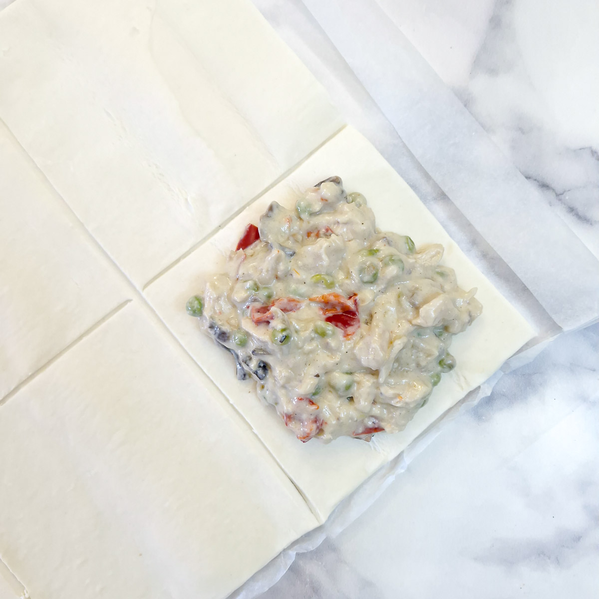 Chicken a la king arraqnged on a square of puff pastry.