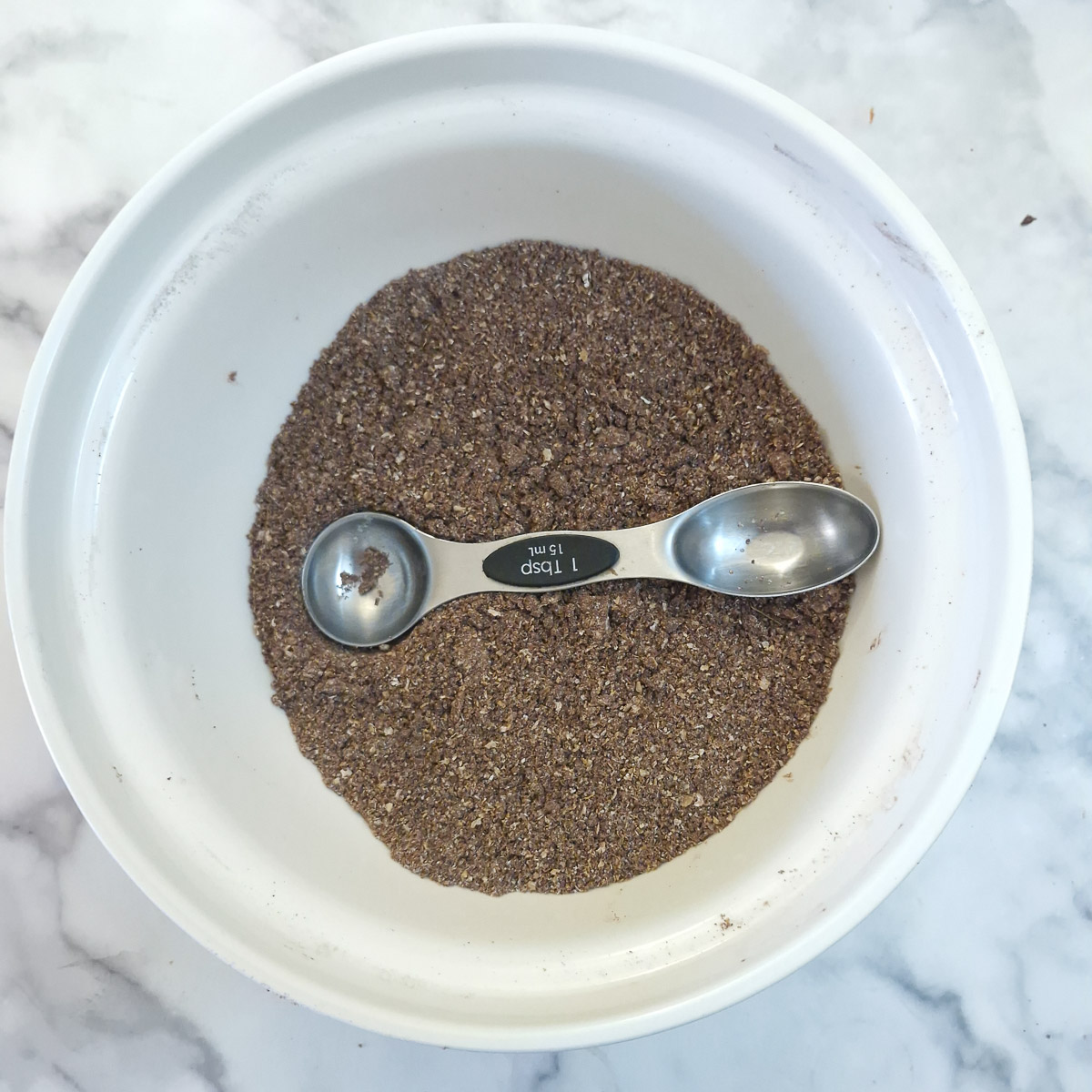A measuring spoon being used to make an indendation in the dry ingredients so the golden syrup can be measured in.